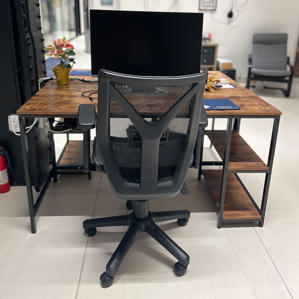 A desk at the DeepTech office viewed from behind the office chair, with a contemporary wood and steel desk, and with a wall with a large screen in the background