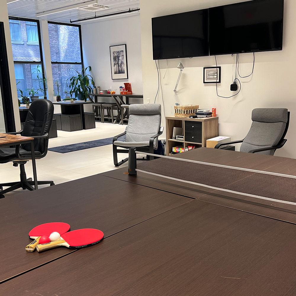 The DeepTech office space showing a ping pong table in the foreground with desks and workstations in the background.