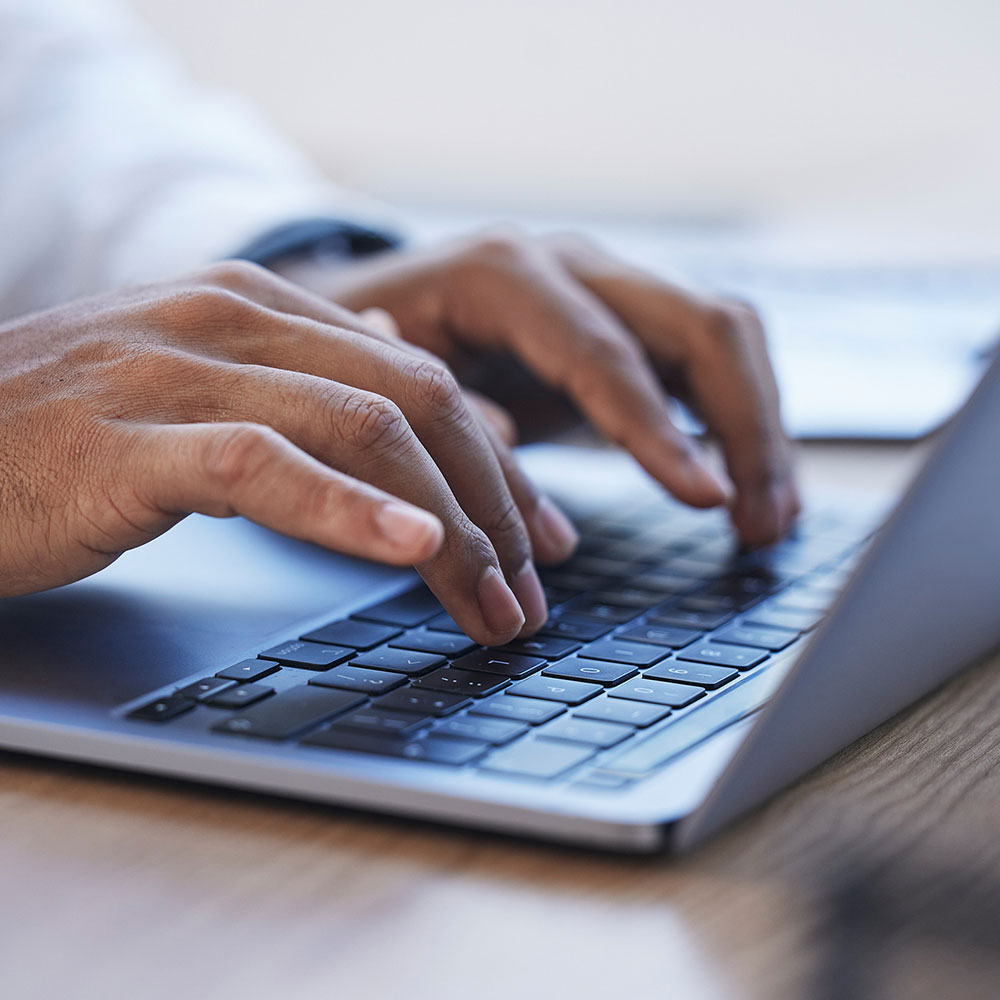 closeup of a pair of hands typing on a laptop keyboard